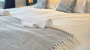 A neatly made bed with rolled white towels, a patterned throw, and two pillows. - Lomond Hills Hotel & Health Club  (Cupar)