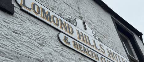 A sign for 'Lomond Hills Hotel & Health Club' on a textured building facade.