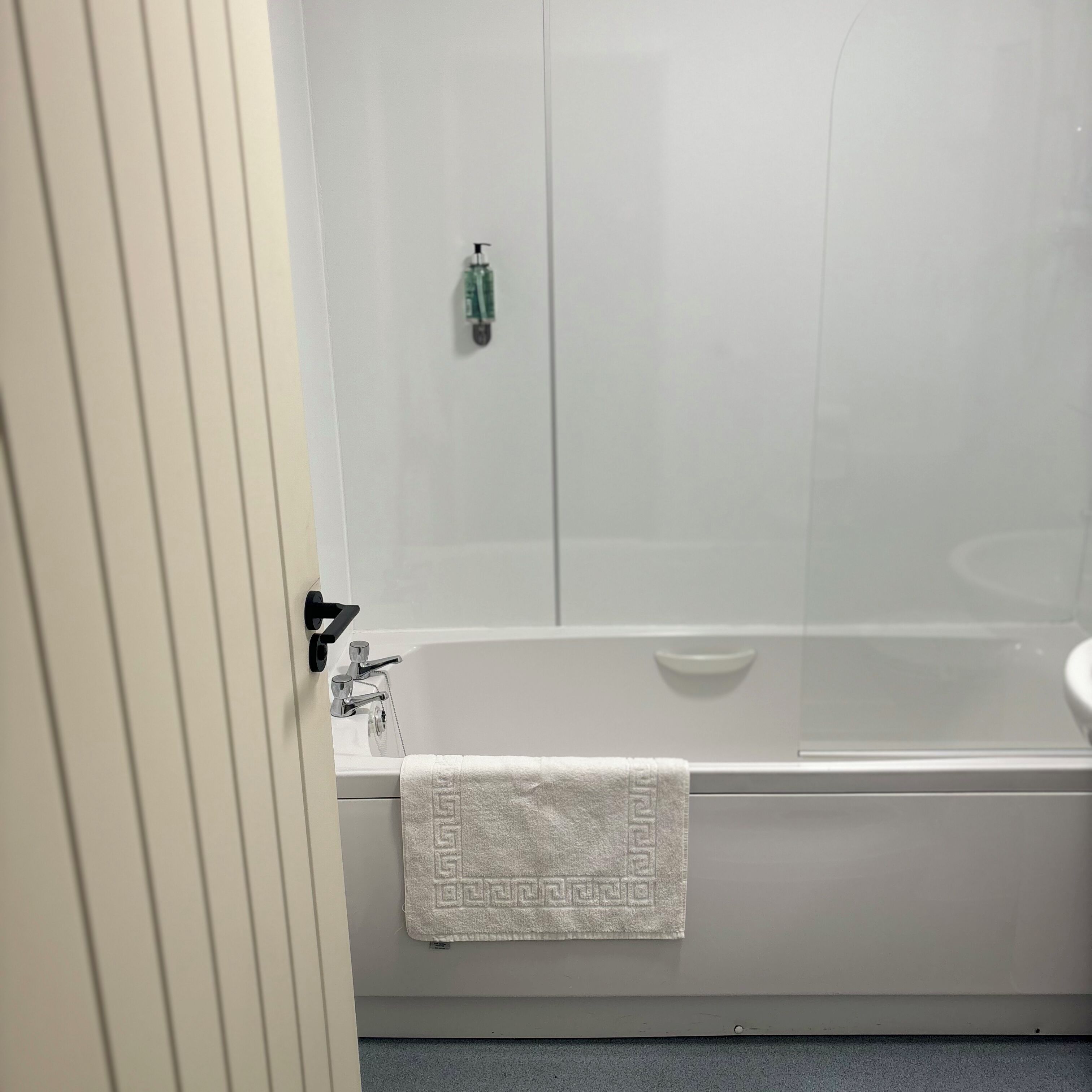 Un bagno con una vasca, un lavandino e un asciugamano appeso al muro.