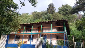 A two-story house with a balcony, a gate, and a small garden area. - Room in Casa de Campo via the airport (Copacabana)