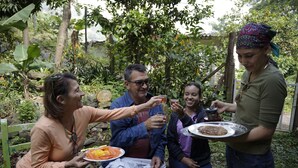 A group of people sitting on a bench outdoors, enjoying a meal with drinks. - Room in Casa de Campo via the airport (Copacabana)
