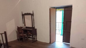A bedroom with a bed, a wooden chair, and a wooden table. - Room in Casa de Campo via the airport (Copacabana)