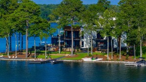 A lakeside property with a modern building, dock, and surrounding trees. - NEW! 151 House on Lake Oconee (Eatonton)