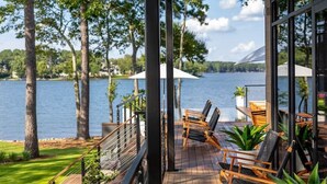 A wooden deck with outdoor seating, overlooking a lake with trees and a mountain in the distance. - NEW! 151 House on Lake Oconee (Eatonton)