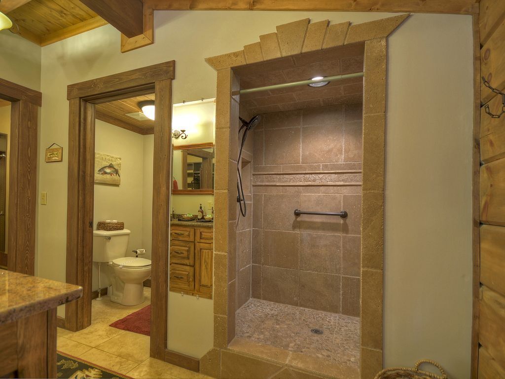 A bathroom with a shower, toilet, and wooden cabinets.