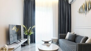 A modern living room with a flat-screen TV, a round coffee table, a sofa, and a decorative wall piece.