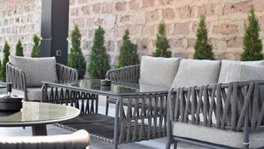 An outdoor seating area with a stone wall backdrop, cushioned chairs, and a round table.