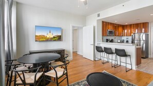 A modern apartment with a dining area, kitchen, and a large window. - Sophisticated 1BR Living w Pool in NOLA (New Orleans)