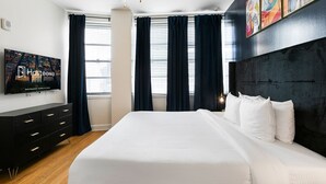 Ett modernt hotellrum med en stor säng, en platt-TV, en byrå i mörk färg och en takfläkt.