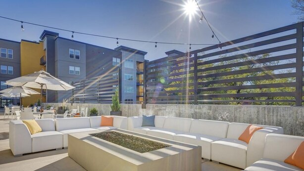 Un área de estar al aire libre con sofás blancos y una jardinera rectangular.