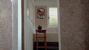 A hallway with a tiled floor leading to a room with a window, a door, and a small table with a vase. - Well located, close to everything (Acapulco de Juárez)