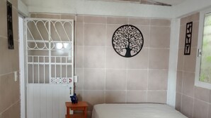 A bedroom with a bed, a ceiling fan, a door with a metal gate, and a wall decoration. - Well located, close to everything (Acapulco de Juárez)