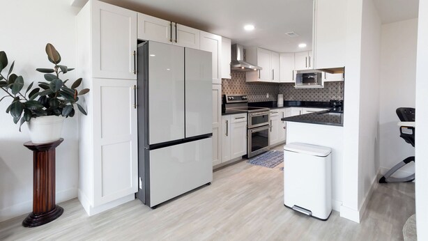 A modern kitchen with white cabinetry, stainless steel appliances, and a built-in microwave.