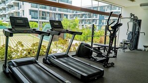 A gym with treadmills, a laptop on one, and exercise equipment in the background. - Makia By Mai (Ipojuca)