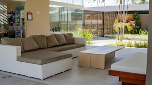 A modern living room with a white sectional sofa, a wooden coffee table, and a small wooden bench. - Makia By Mai (Ipojuca)