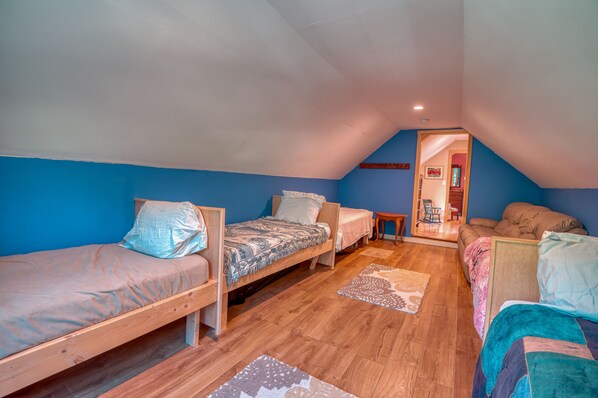 A dorm-style room with two beds, a sofa, and a small table.