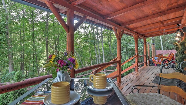 A wooden deck with a table set for two, surrounded by a forest. - Sunset Serenity Luxury Cabin with Hot Tub Pet Friendly (Elizabethton)