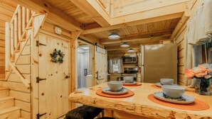A wooden interior with a kitchen area featuring a dining table set with bowls and plates, a microwave, and a refrigerator. - Sunset Serenity Luxury Cabin with Hot Tub Pet Friendly (Elizabethton)