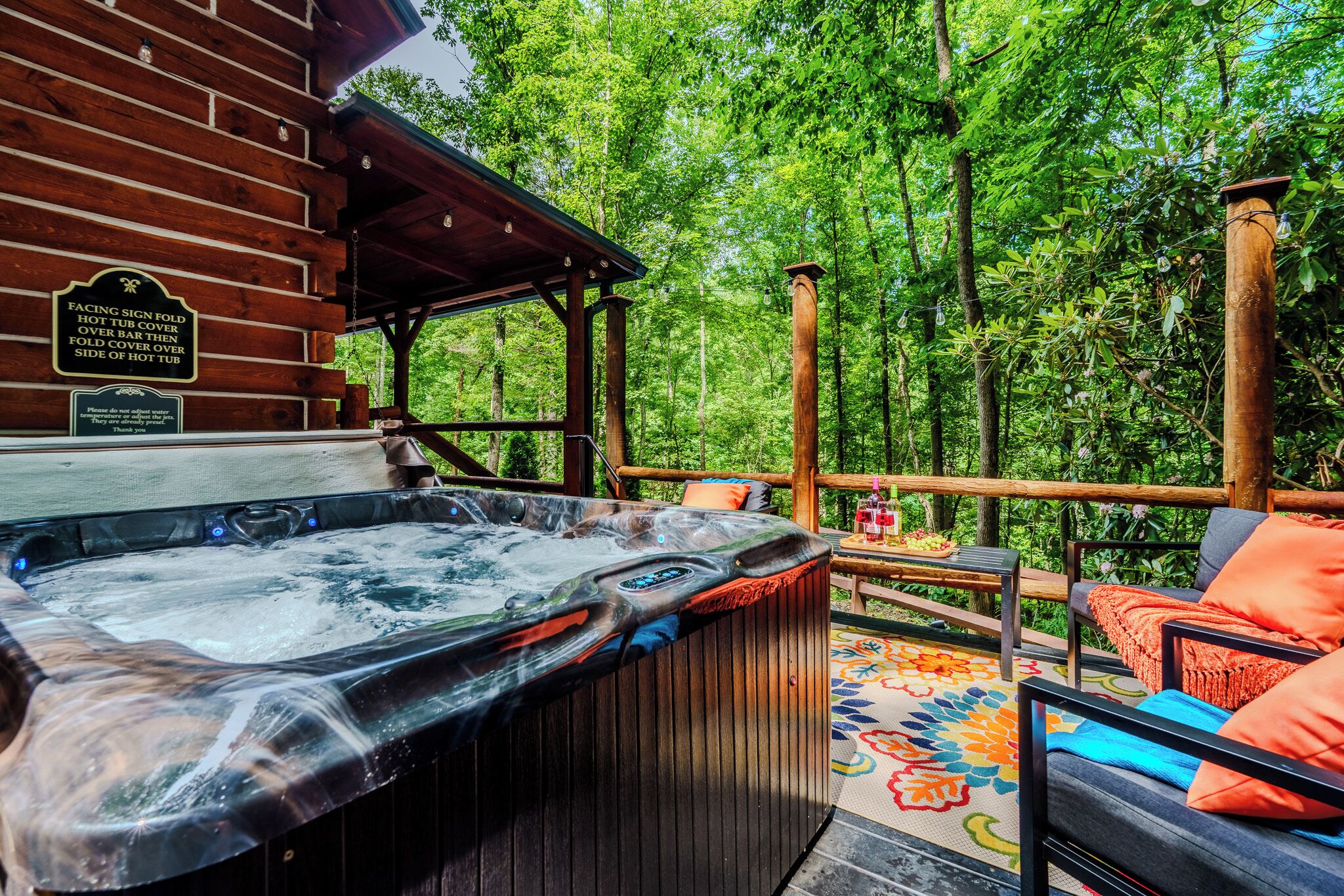 A hot tub with a wooden deck, surrounded by lush greenery.