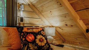 A wooden cabin interior with a bed, pillows, and a window. - Sunset Serenity Luxury Cabin with Hot Tub Pet Friendly (Elizabethton)