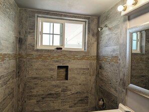 Bathroom features a large window, shelf, and decorative mirror.