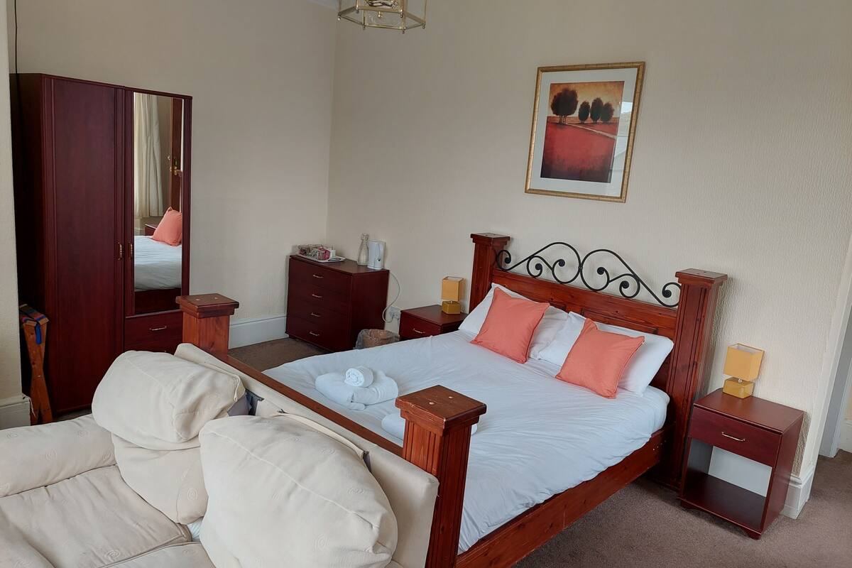 A neatly arranged bedroom with a wooden bed, a wardrobe, a bedside table, and a chair.