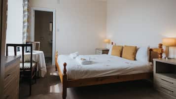 Une chambre à coucher avec un lit en bois, une table de chevet avec une lampe, une petite table avec une chaise et une armoire.