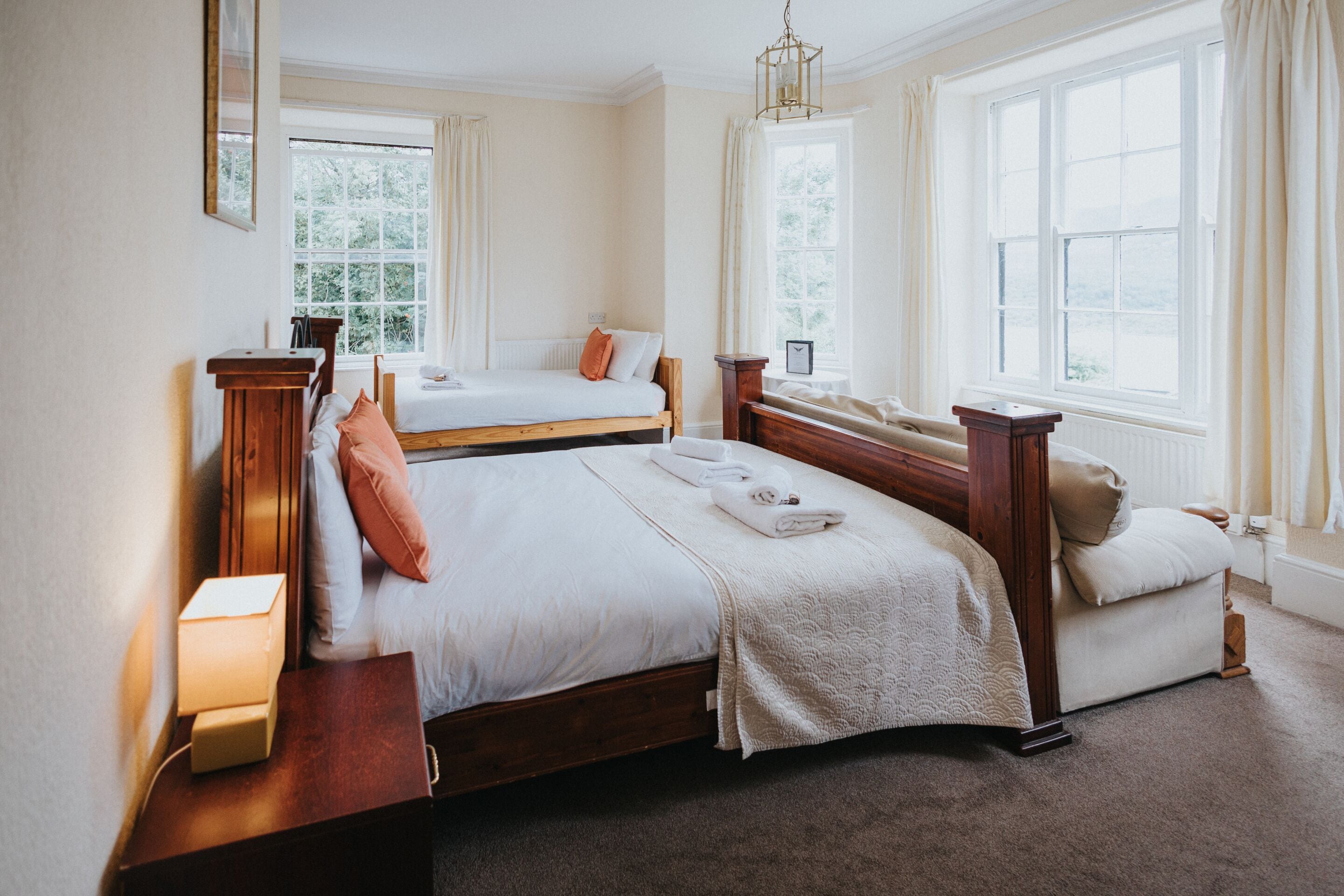 Een slaapkamer met twee bedden, een nachtkastje en een raam met gordijnen.
