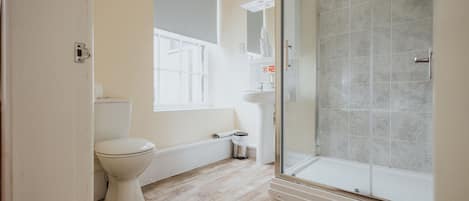 Un baño con inodoro, ducha con puerta de cristal y lavabo.