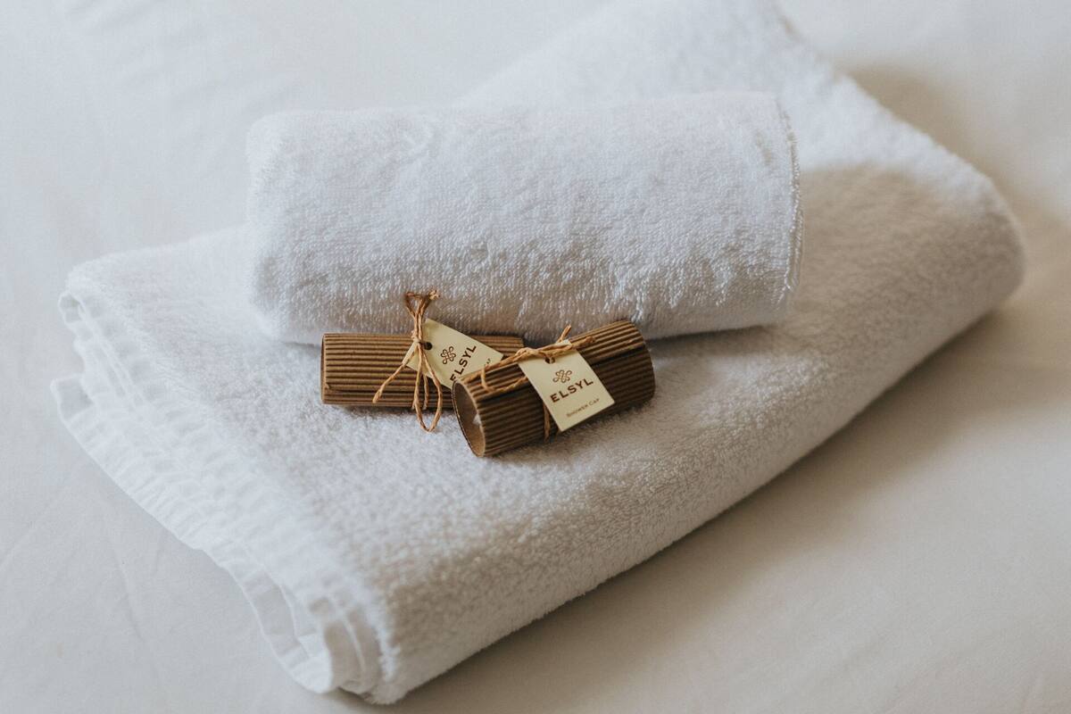 A neatly folded white towel with a tag on a bed.