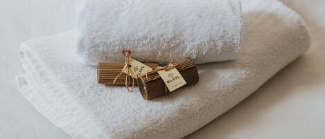 A neatly folded white towel with a tag on a bed.