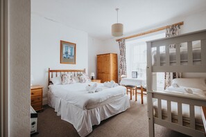 A bedroom with a large bed, a wooden wardrobe, a desk, and a crib. - Y Pengwern (Blaenau Ffestiniog)