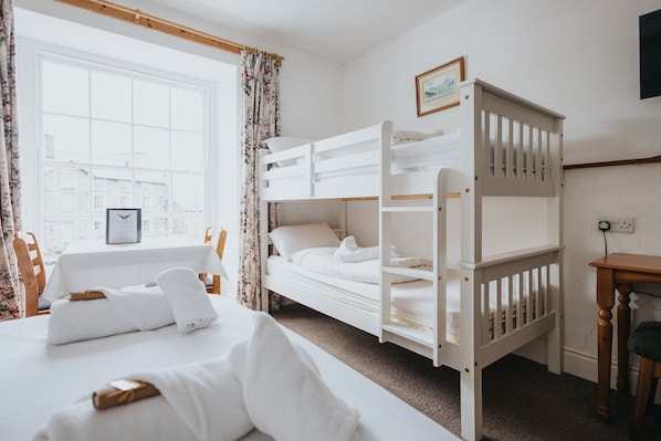 A hotel room with a bunk bed, a desk, a chair, a window with curtains, and a framed picture on the wall. - Y Pengwern (Blaenau Ffestiniog)