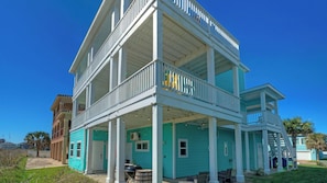 A two-story building with a balcony, a covered porch, and a staircase leading to the upper level. - Coastal Soiree Ocean Views, Game Room, & Steps From Port Aransas Beaches (Port Aransas)
