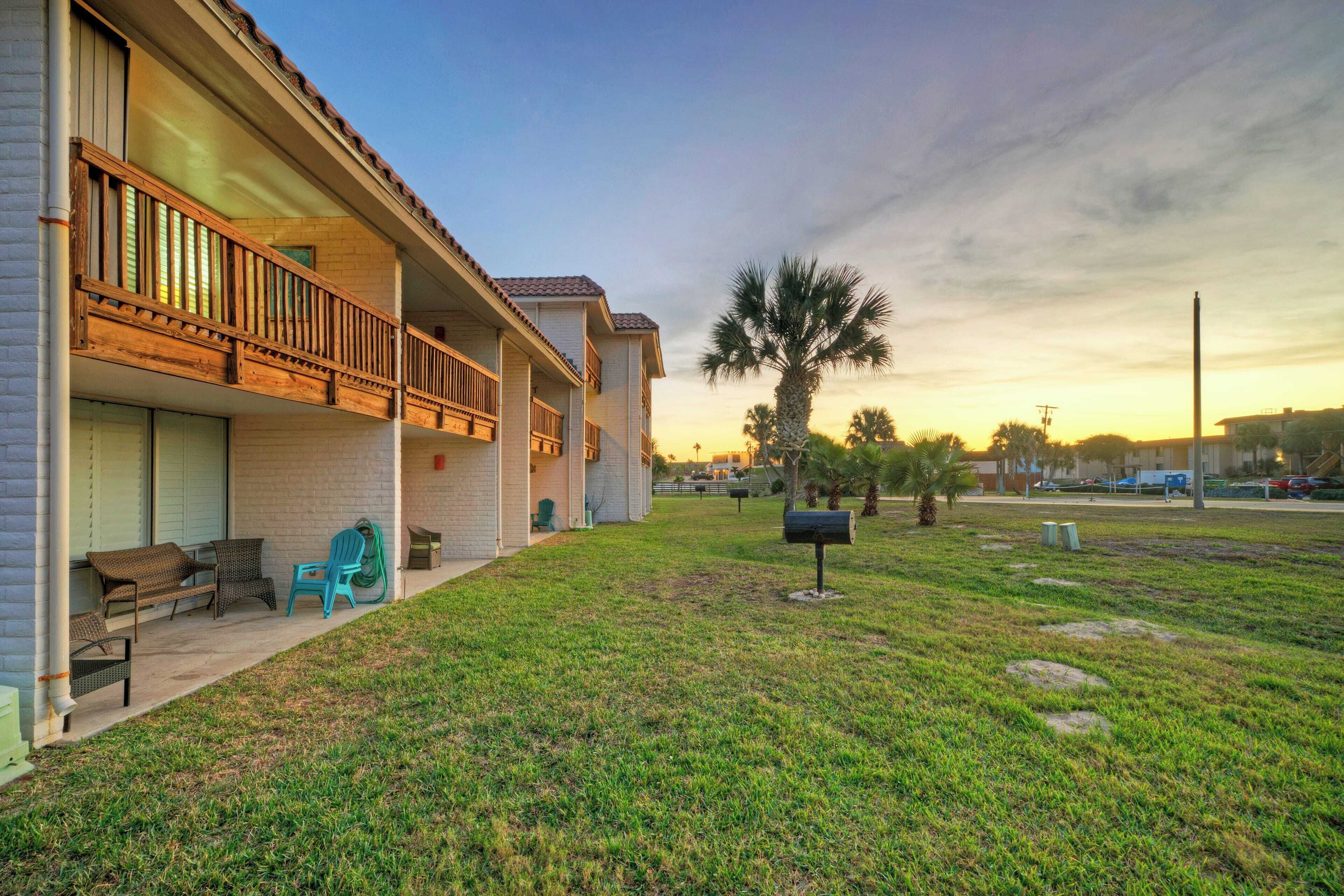 A two-story building with a balcony, outdoor seating, and a well-maintained lawn.