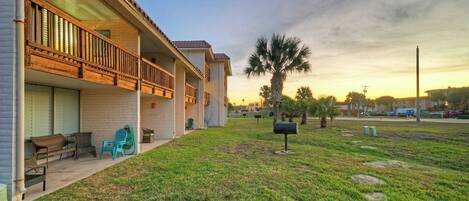 A two-story building with a balcony, outdoor seating, and a well-maintained lawn.
