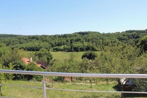 A rural landscape with a house surrounded by greenery and trees.