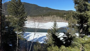 Un paisaje montañoso con cielo despejado, bosque denso y zona cubierta de nieve.