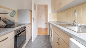 Una cocina compacta con estufa, horno, lavaplatos y armarios.