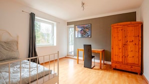 Un dormitorio con cama, escritorio, silla, armario y un cuadro en la pared.