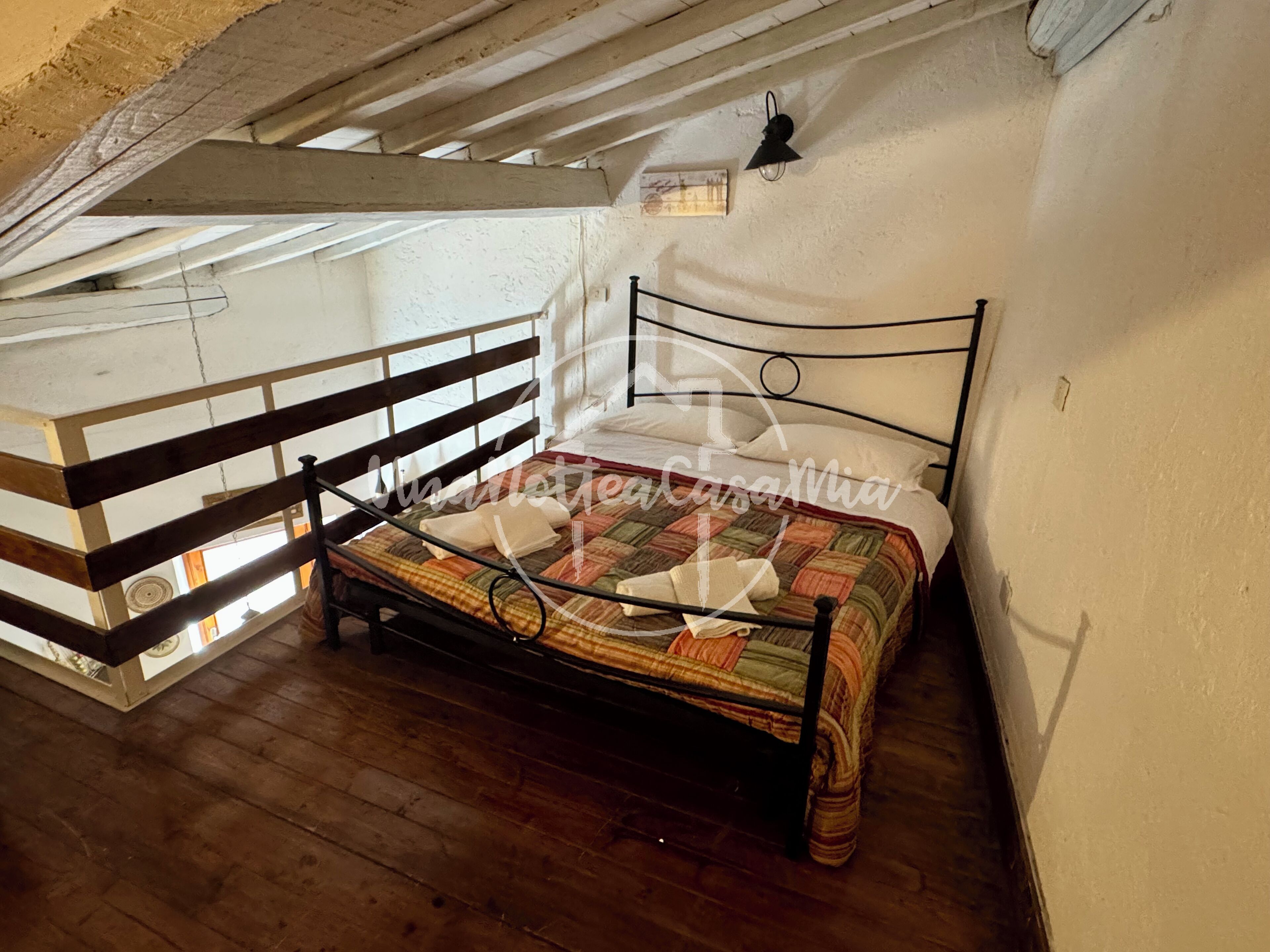 Ein Schlafzimmer mit einem Holzbett, einer geneigten Decke und einem kleinen Balkon.