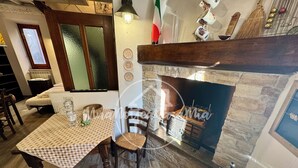 A cozy room with a checkered table, wooden chairs, a stone fireplace, and a window with frosted glass. - La Scalinatella "UnaNotteaCasaMia" (SACROFANO)