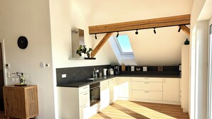A modern kitchen with a skylight, wooden flooring, and white cabinetry. - "Seeblick" guest house - Bright penthouse apartment on the outskirts of Salzburg (Seekirchen am Wallersee)