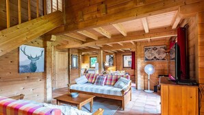 L'intérieur d'un chalet en bois, avec un canapé, une table à manger et un téléviseur.