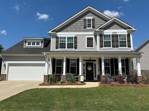 A two-story house with a garage, a covered porch, and a well-maintained lawn. - Master's Tournament Rental House (Grovetown)
