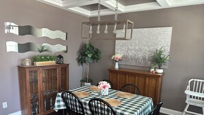 A dining room with a checkered tablecloth, wooden chairs, a chandelier, and decorative mirrors. - Master's Tournament Rental House (Grovetown)