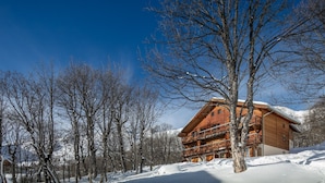 A wooden chalet with a balcony, surrounded by snow-covered trees and a clear blue sky. - Les Grizzlis N°27 - 2P6C (Saint-Sorlin-d´Arves)