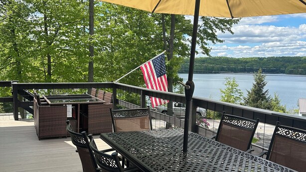 Eine Terrasse mit Tisch und Stühlen, einer amerikanischen Flagge und Blick auf einen See.