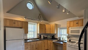 Een keuken met houten kastjes, een koelkast, een fornuis en een magnetron.