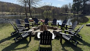 Een zitgedeelte aan het meer met Adirondack-stoelen rond een vuurkuil.